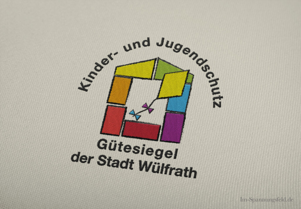 gesticktes buntes Logo mit farbigen Bauklötzchen und einem Rundsatz Kinder- und Jugendschutz Gütesiegel der Stadt Wülfrath